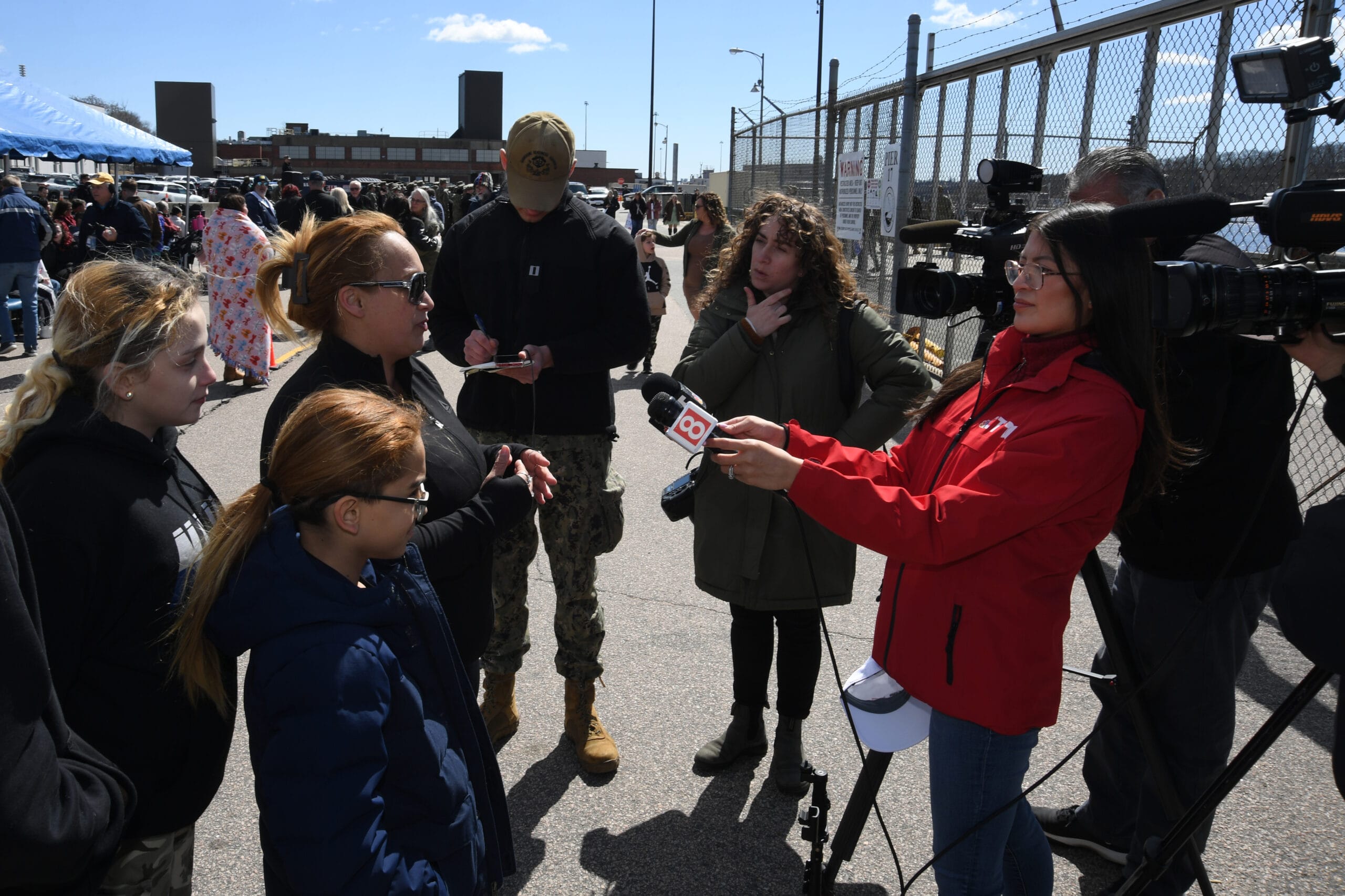A Navy spouse embraces a service member at the pier
