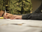 A Navy recruit signing an enlistment contract at a MEPS office