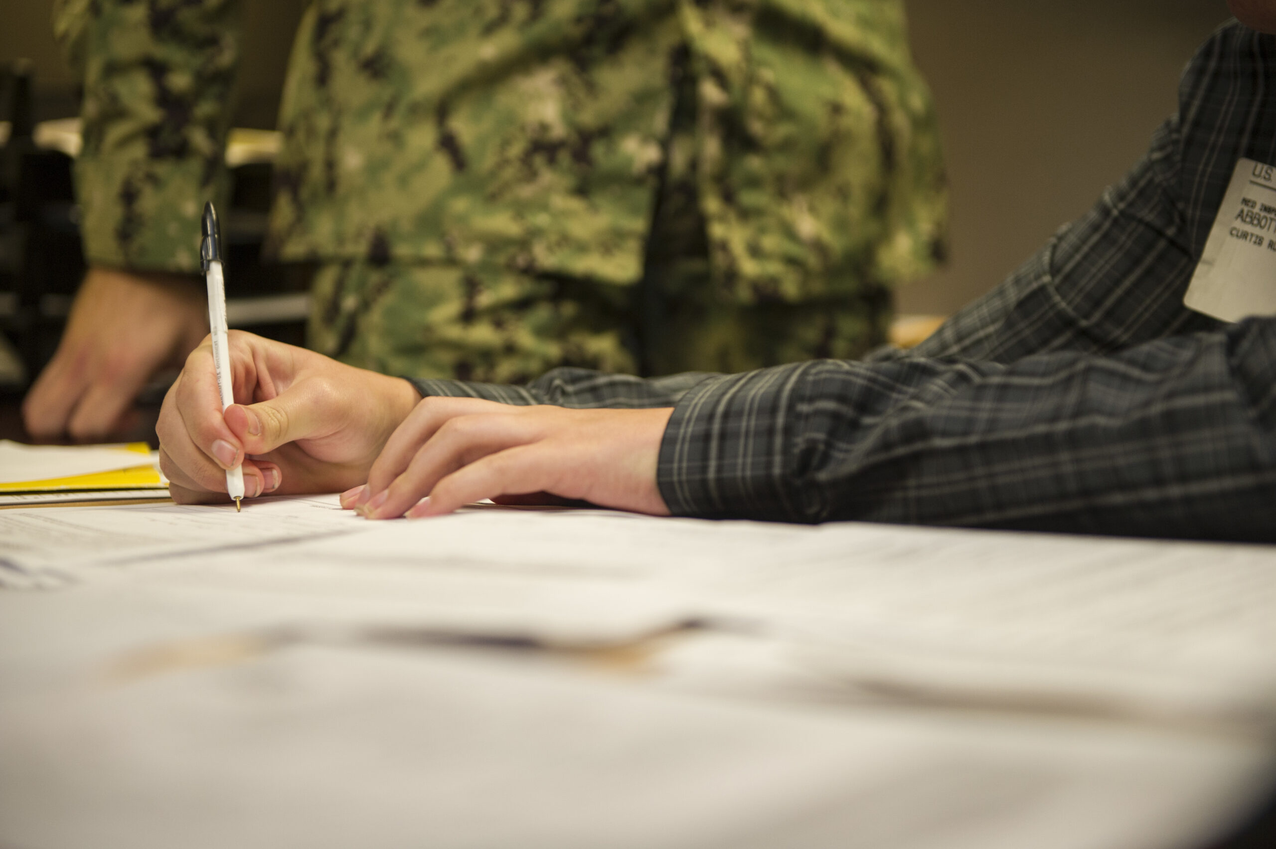 A Navy recruit signing an enlistment contract at a MEPS office