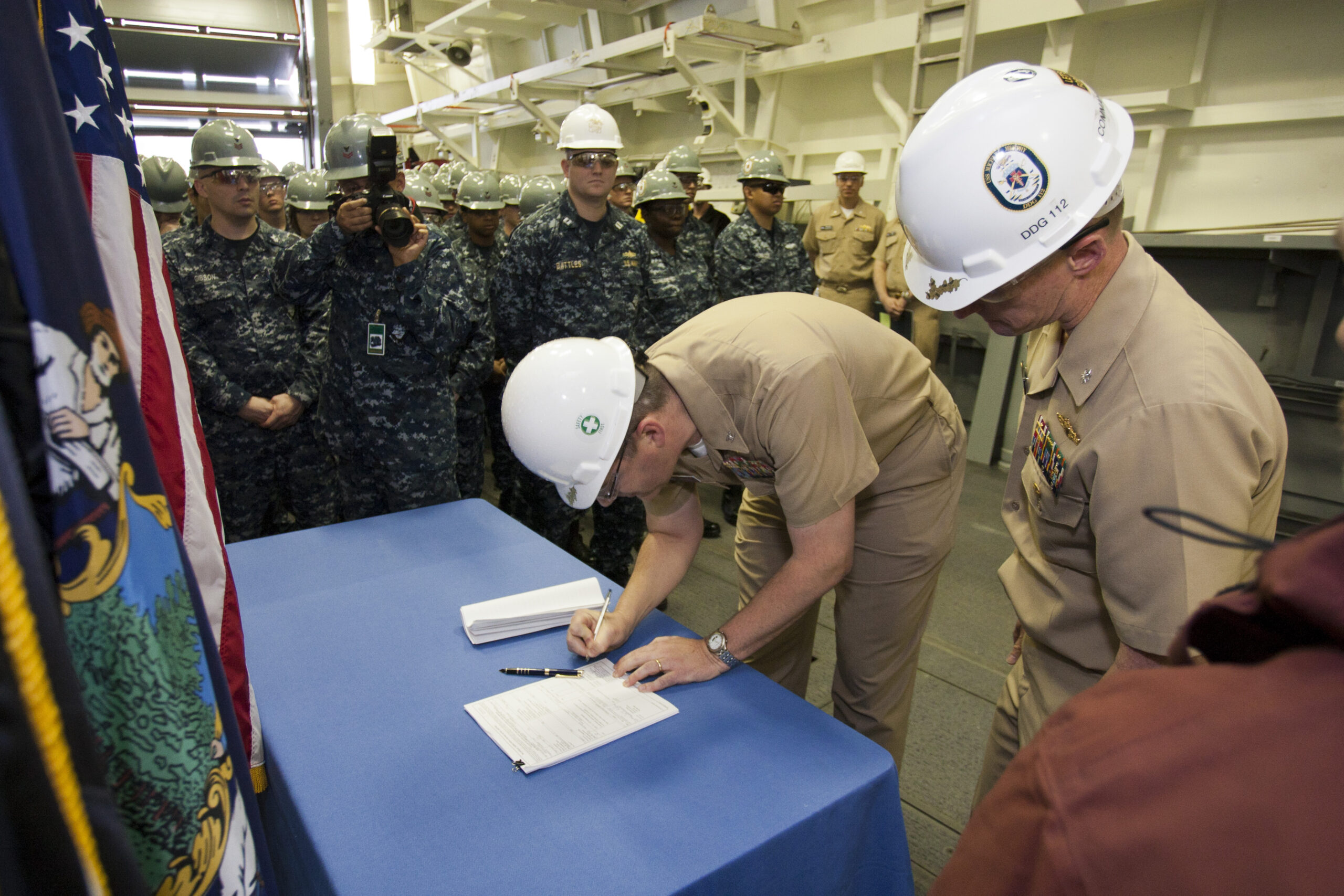 A Navy officer signs loan documents at a closing table